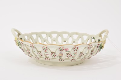 Lot 20 - A Worcester round basket, circa 1770, polychrome painted with flowers, the handles with flower and leaf terminals, the outside with applied florets picked out in puce and green, 17cm wide