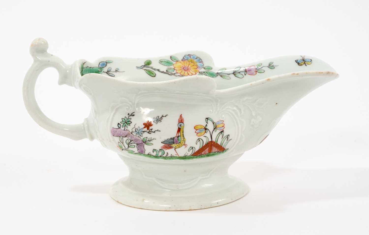 Lot 9 - An early Worcester moulded sauceboat, circa 1753-54, finely painted in polychrome enamels with birds amongst trees and rockwork in the Chinese style, within moulded cartouches on each side, flow...