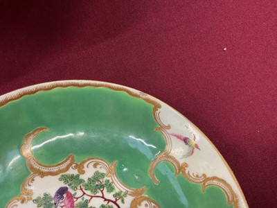 Lot 29 - A Worcester coffee cup and saucer, circa 1770, painted in coloured enamels with exotic birds, within gilt 'C' scroll cartouches, the apple-green ground with gilt scroll borders, panelled with sm...