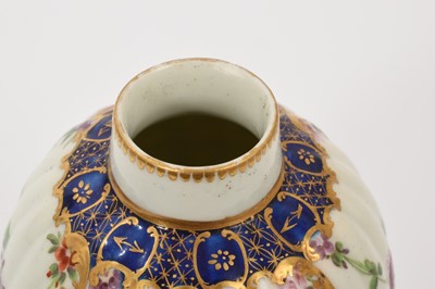 Lot 40 - A Worcester tea caddy, circa 1780, of fluted form, polychrome painted with floral swags in gilt panels, with a blue and gilt border, gilt dentil rim, the bottom with shagreen pattern, W mark to...
