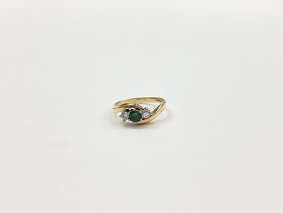 Lot 1021 - 18ct gold diamond and emerald three stone ring in cross over setting