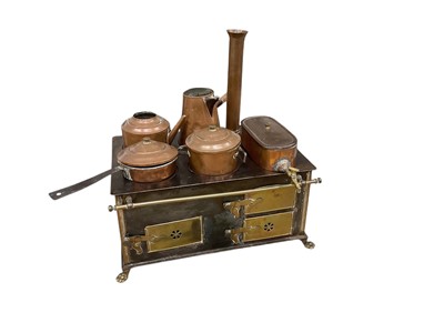 Lot 27 - A miniature Victorian style stove, early 20th century, of rectangular form fitted with a variety of copper kettles and pans, the stove with decorative brass fittings, on lion paw feet, 35cm wide...