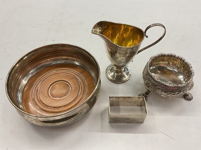 Lot 1141 - Silver wine coaster, Victorian silver cream jug, silver cauldron salt and a silver rectangular napkin ring (4)