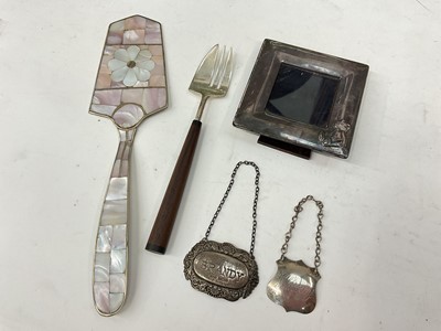 Lot 1120 - Contemporary silver photograph frame, silver brandy label, plated whiskey label, silver Linley fork with wooden handle and a white metal mother of pearl cake slice