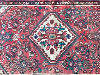 Lot 1433 - Hamadan runner with three medallions and geometric ornament on brick-red ground, 342cm x 76cm