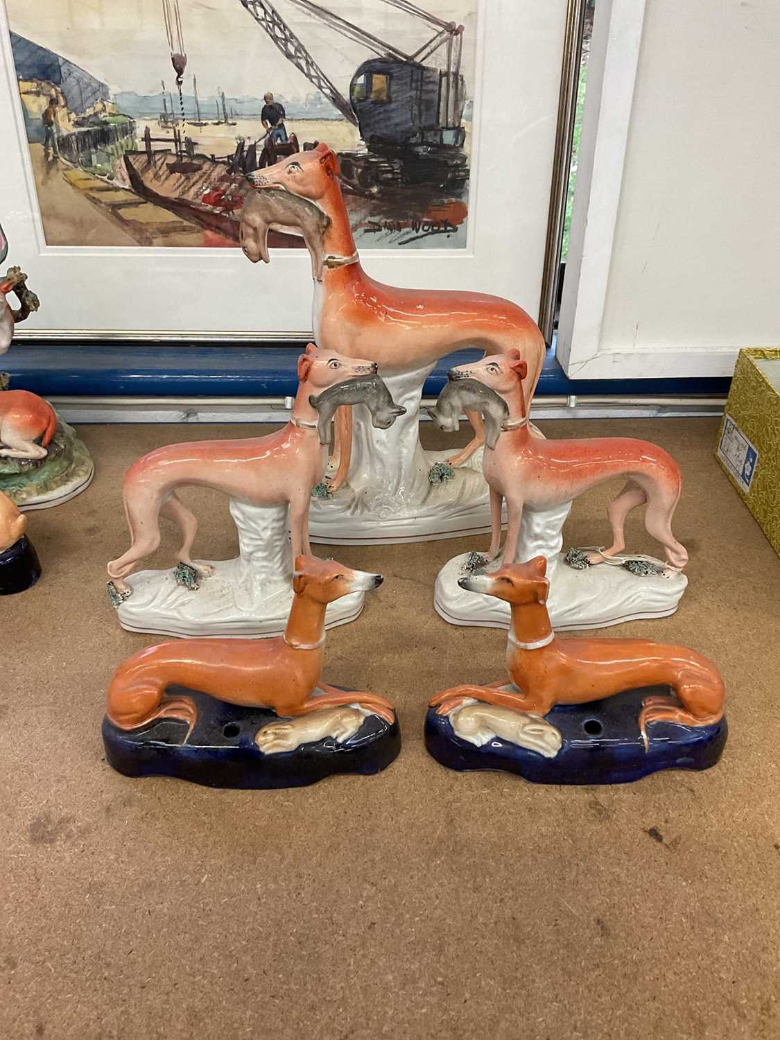 Lot 73 - Pair of Victorian Staffordshire greyhound inkwells, and a garniture of standing greyhounds with rabbits in their mouths (5)