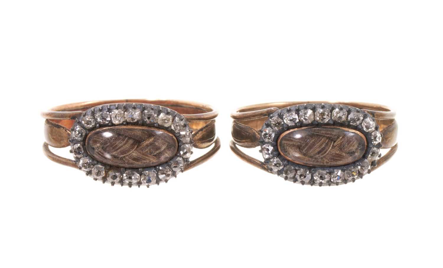 Lot A very rare pair of George III gold and diamond mourning rings, each with a glazed compartment of plaited hair surrounded by a border of old cut diamonds, with pierced shoulders on tapered gold...