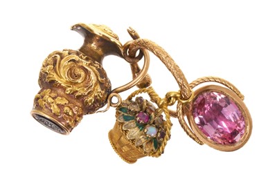 Lot Three Regency novelty charms/seals, to include a yellow metal multi-gem and enamel basket, another yellow metal basket with foil-backed pink stone and intaglio seal with Cupid, and a yellow meta...