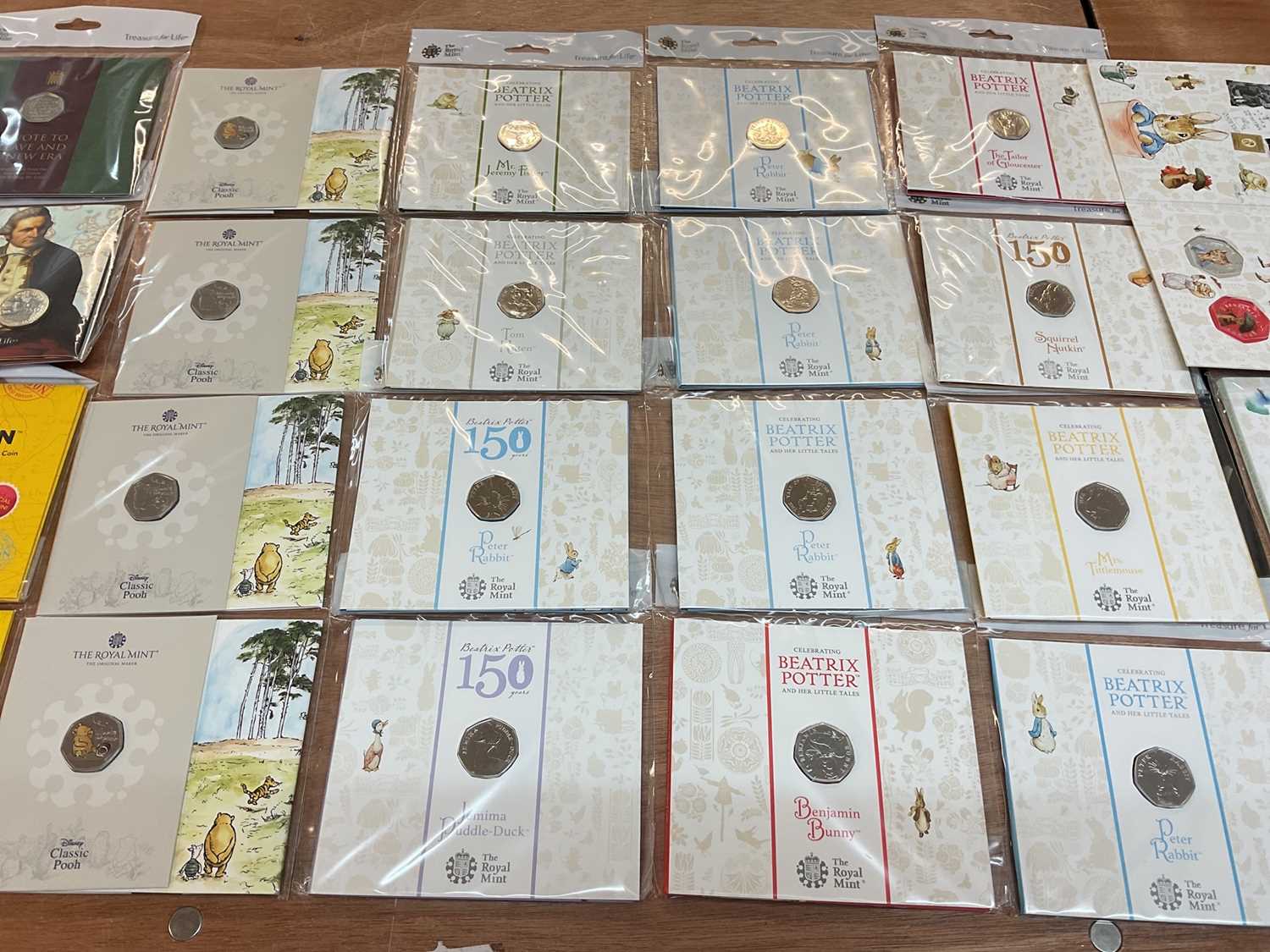 Lot 493 - G.B. - Royal Mint uncirculated flatpack coins to include Fifty Pence Beatrix Potter x 14, Classic Pooh x 4, Paddington Bear x 2, Beatrix Potter Treasure of Life coin collection album 2017 (N.B....