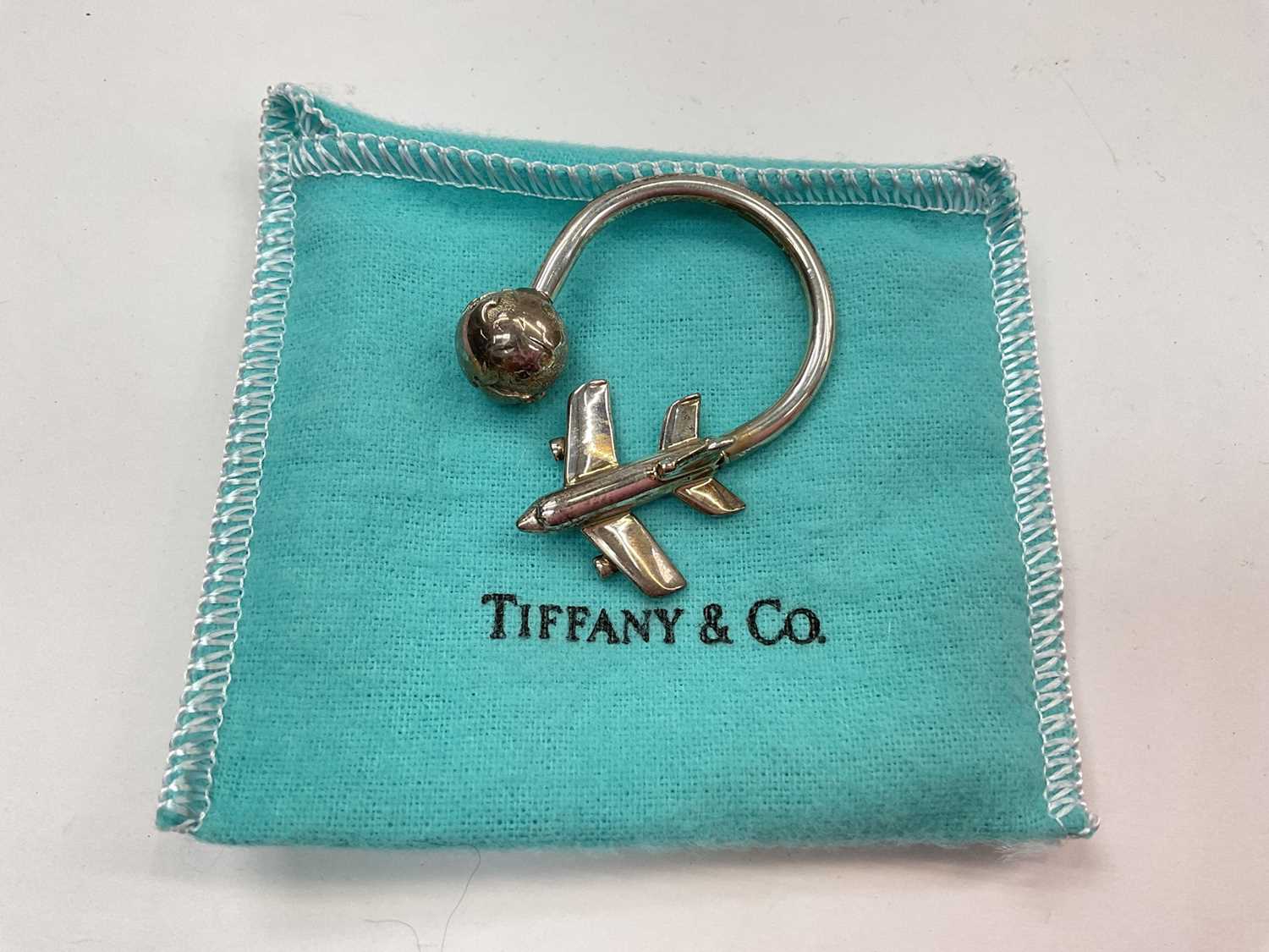 Lot 1010 - Tiffany & Co silver aeroplane and globe key ring (London 1999), in pouch
