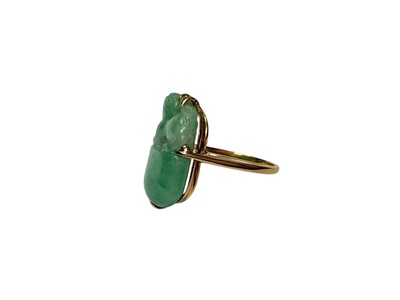 Lot 13 - Carved jade/ green hardstone ring depicting a dog of foo, in a yellow metal mount. Ring size K½