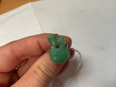Lot 13 - Carved jade/ green hardstone ring depicting a dog of foo, in a yellow metal mount. Ring size K½