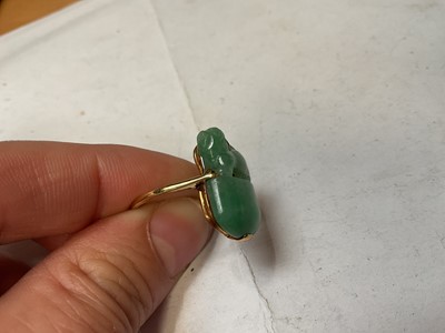 Lot 13 - Carved jade/ green hardstone ring depicting a dog of foo, in a yellow metal mount. Ring size K½
