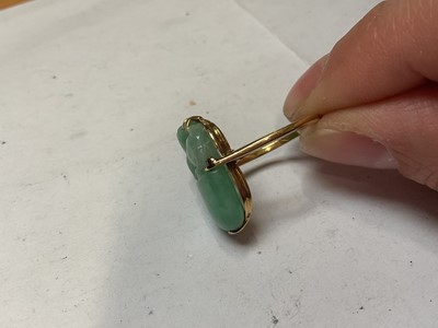 Lot 13 - Carved jade/ green hardstone ring depicting a dog of foo, in a yellow metal mount. Ring size K½