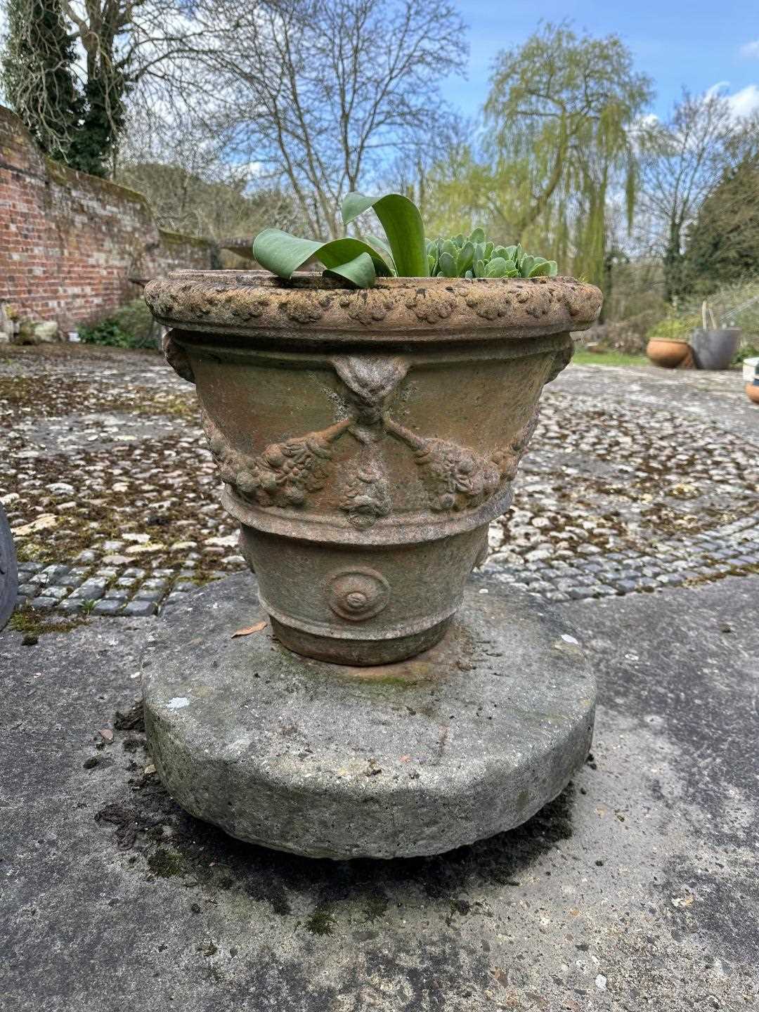 Lot 1505 - Antique millstone, 60cm diameter, together with a terracotta pot, 46cm high