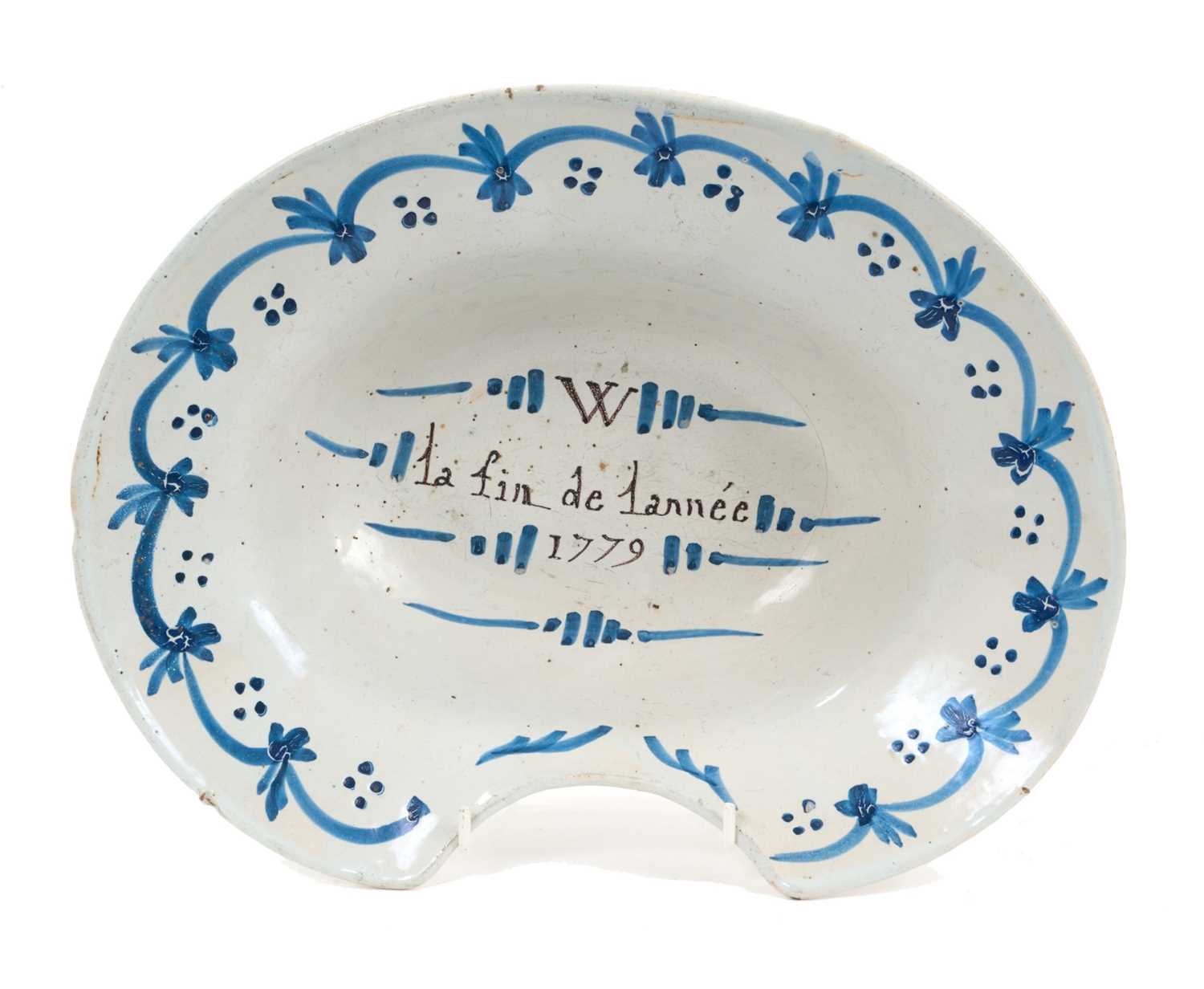 Lot 34 - Rare 18th century French faience barber's bowl, inscribed 'W - la fin de lannée 1779', with blue swag and dot border, 30.5cm wide