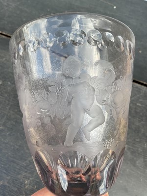 Lot 26 - Large Bohemian cut and engraved glass goblet and domed cover, circa 1730, well engraved with five putti around the body struggling with a heavy swag of pomegranates, grapes and other fruit, be...
