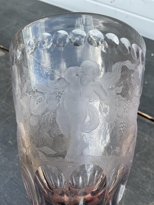 Lot 26 - Large Bohemian cut and engraved glass goblet and domed cover, circa 1730, well engraved with five putti around the body struggling with a heavy swag of pomegranates, grapes and other fruit, be...