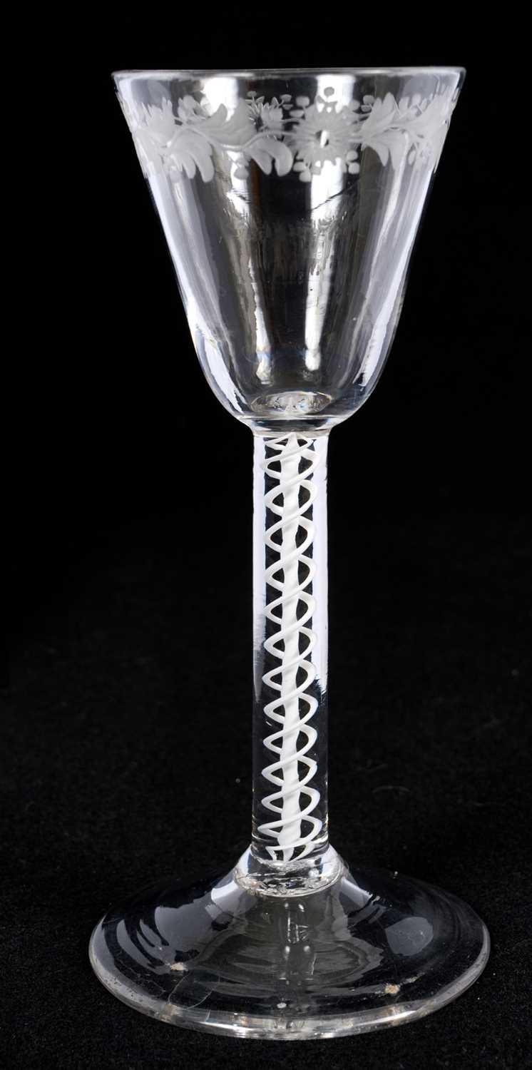 Lot 24 - Opaque twist wine glass, circa 1760, with tapering funnel bowl, engraved at the rim with flowers and foliage, on a straight double series opaque twist stem and domed foot, 15cm high