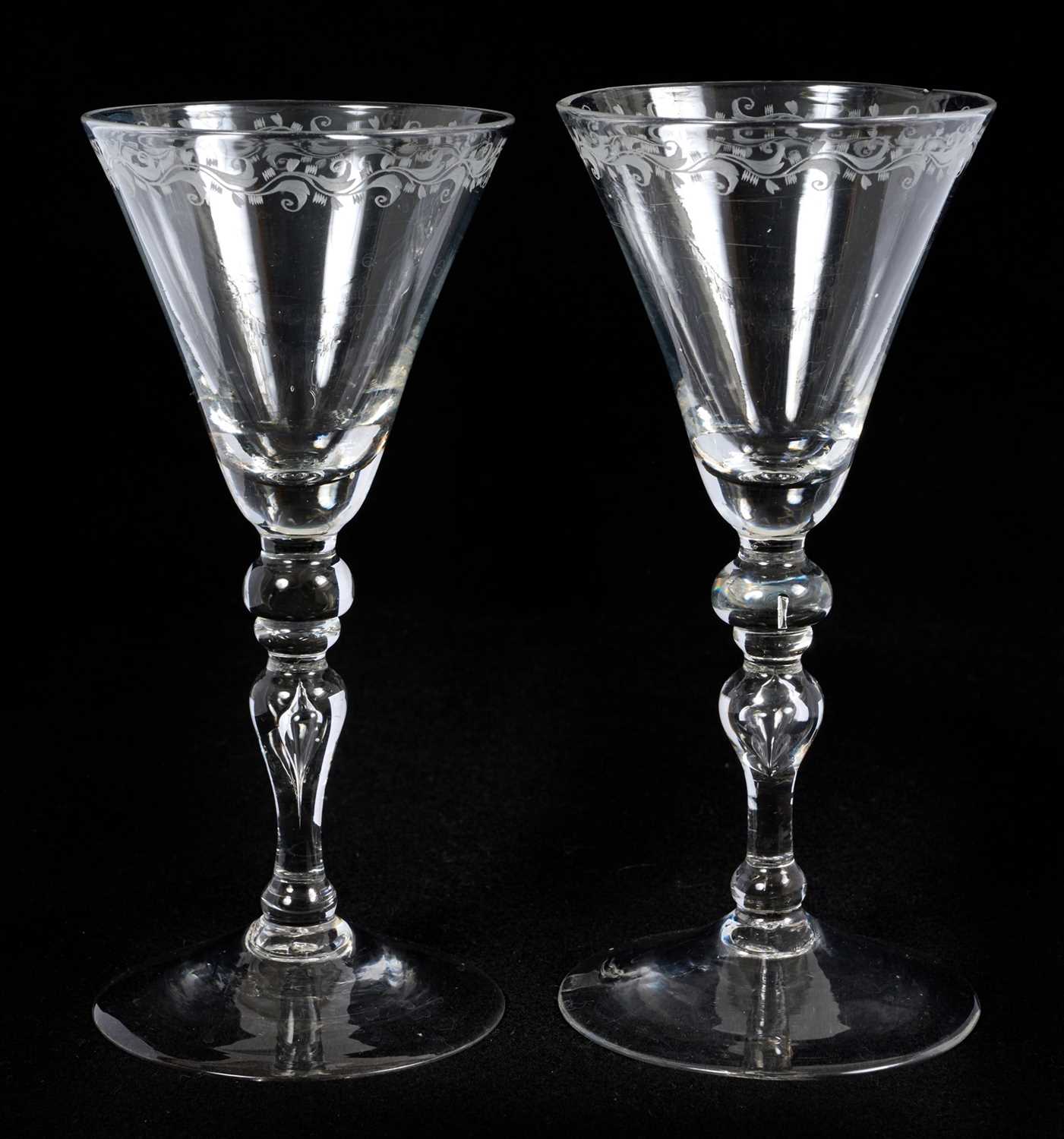 Lot 22 - Pair of light baluster wine glasses, circa 1730, with tapering funnel bowls, knopped and cushioned baluster stems with tear-drop, on a conical foot, the rim engraved with a band of scrolling f...