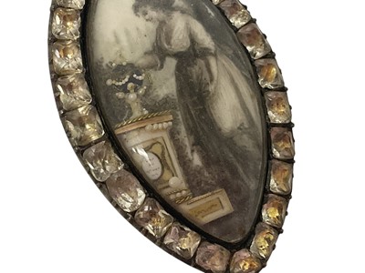 Lot 450 - George III mourning brooch of navette form, the ivory plaque painted in sepia depicting a lady standing by a gold and seed pearl urn on pedestal