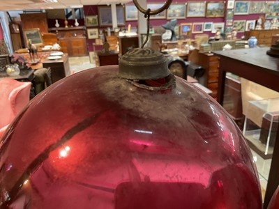 Lot 799 - Two red glass witch balls, each approximately 18cm and 14cm diameter respectively