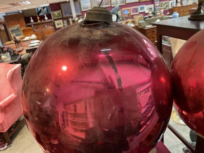 Lot 799 - Two red glass witch balls, each approximately 18cm and 14cm diameter respectively