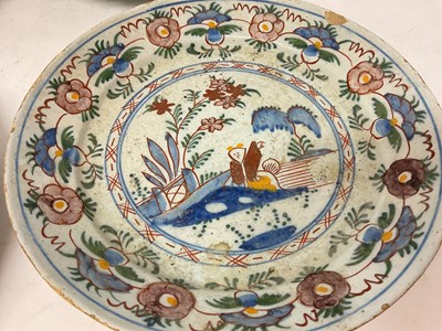 Lot 131 - Four 18th century Delft plates, including one with a Chinese figure in a garden, 22cm to 23cm diameter (4)