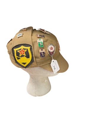 Lot 716 - Cold War era Soviet cap with various enamel and cloth badges attached