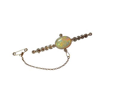 Lot 90 - Opal and diamond gold bar brooch with a central oval polished opal in a millegrain setting flanked by four old cut diamonds and further diamond set leaves to the bar