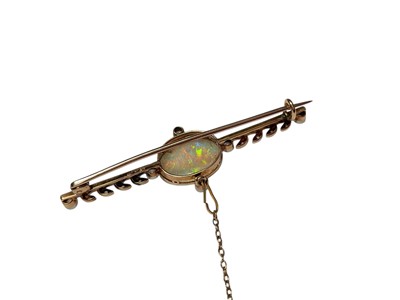 Lot 90 - Opal and diamond gold bar brooch with a central oval polished opal in a millegrain setting flanked by four old cut diamonds and further diamond set leaves to the bar