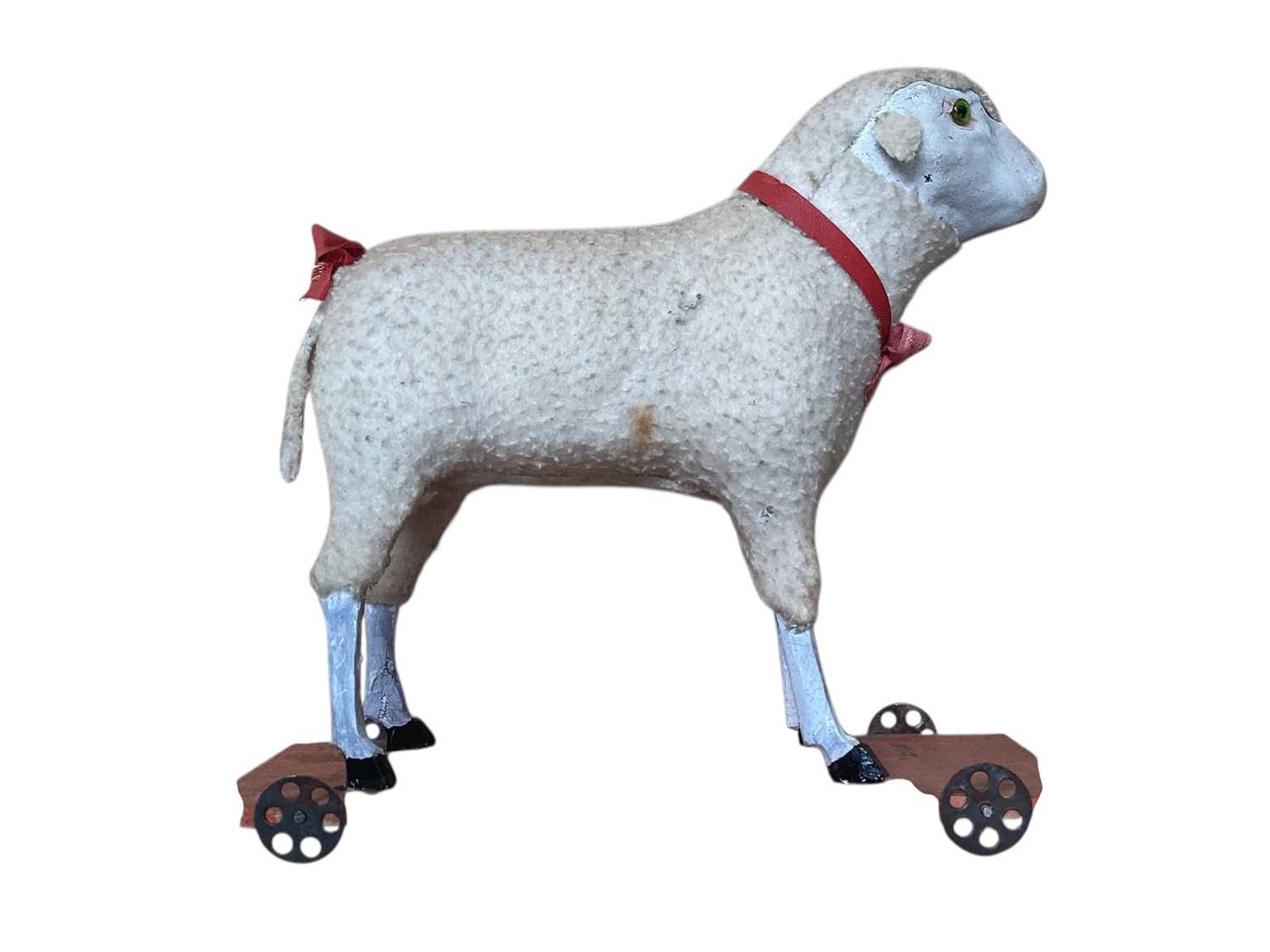 Lot 1820 - Two early Putz sheep with painted faces, green glass eyes, wool plush and wooden stick legs, 15cms and 18cms approximately . Plus similar dog with amber glass eyes 15cms.