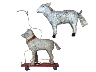 Lot 1820 - Two early Putz sheep with painted faces, green glass eyes, wool plush and wooden stick legs, 15cms and 18cms approximately . Plus similar dog with amber glass eyes 15cms.