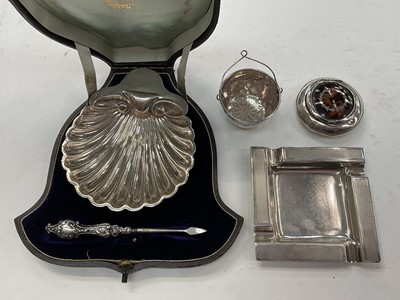 Lot 1082 - Group of silver to include a shell shaped butter dish in case, 1950s silver ashtray, silver and tortoiseshell box, silver handled manicure tool and a continental white metal strainer