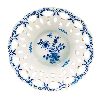 Lot 220 - An 18th century English porcelain basket, probably Lowestoft, the sides pierced with interlacing circles, florets applied to the exterior, painted in blue with a floral spray and flying insect t...
