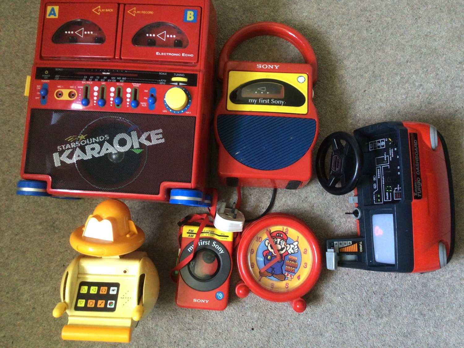 Lot 1997 - 1980's Sony red First Cassette player, Karioke and Walkman. Mario Brothers clock, 1980's Goast Busters backpack and Proton Pack, Binatone TV game boxed, Amiga Manual and other books, Guitar Hero...
