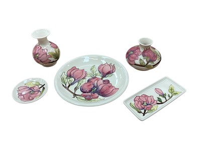 Lot 1016 - Six pieces of Moorcroft pottery all decorated in the Magnolia pattern on ivory ground, including three vases, pen tray, pin dish and plate