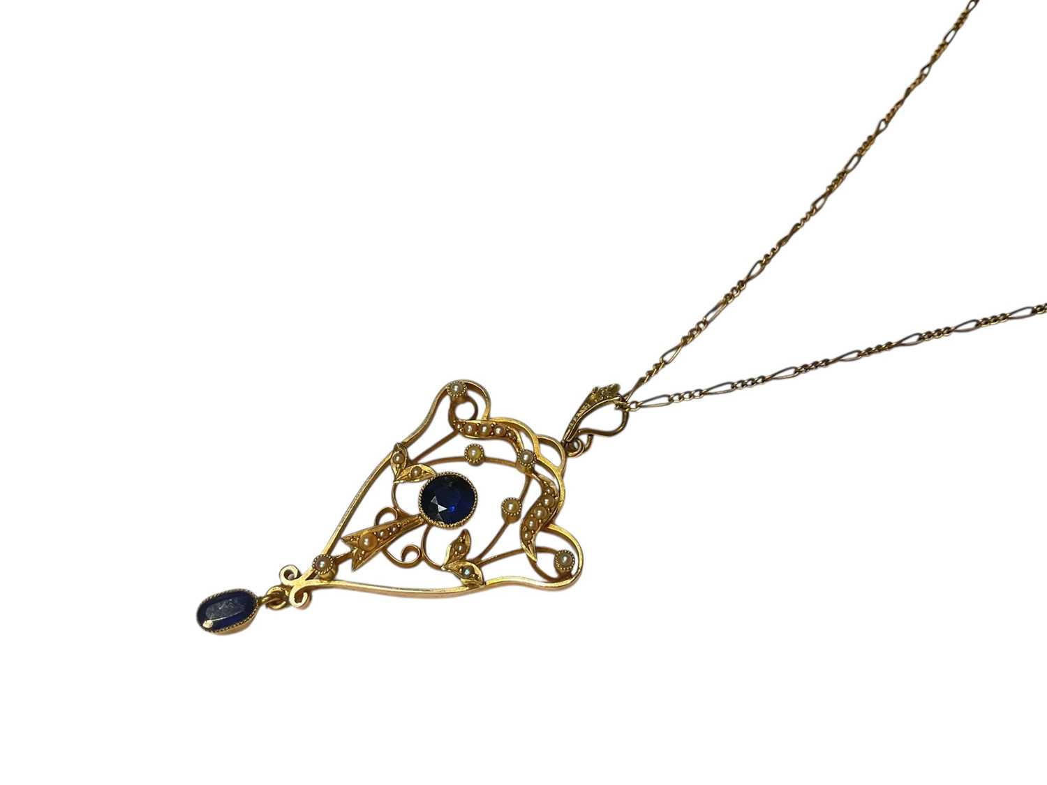 Lot 126 - Edwardian 15ct gold sapphire and seed pearl open work scroll pendant on a gold plated chain