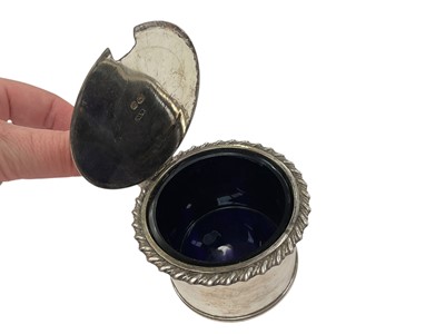 Lot 137 - Early Victorian silver mustard pot of drum form with gadrooned border, reeded angular handle and interior with blue glass liner, (London 1838), 5.1cm in overall height.