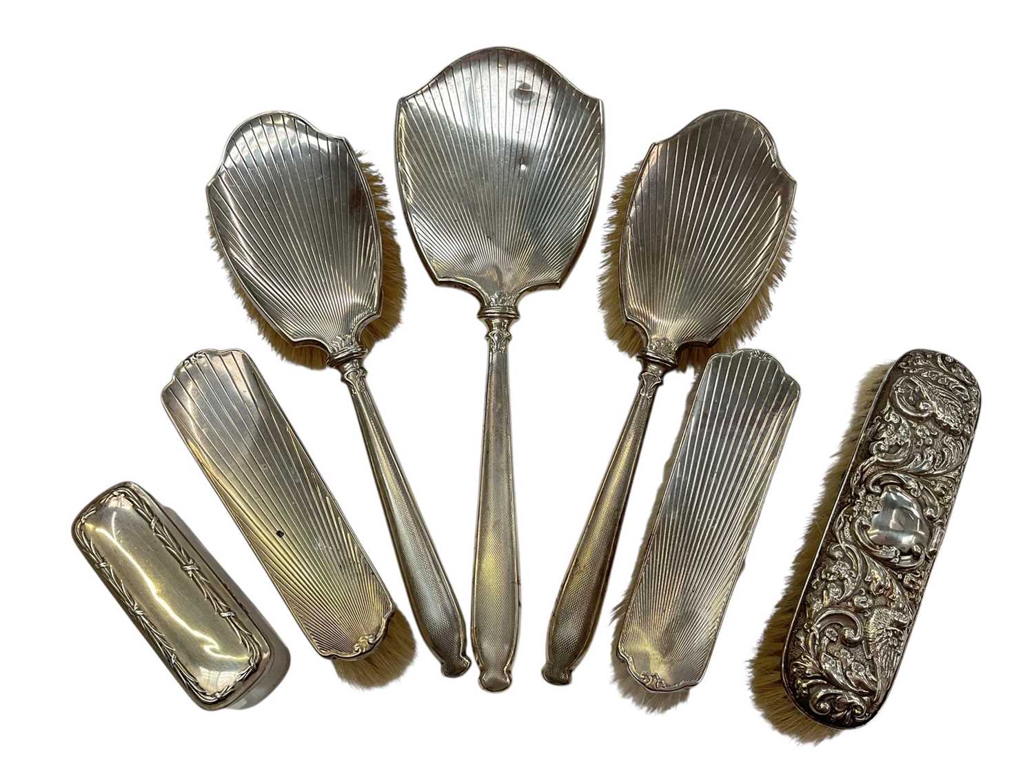 Lot 141 - George VI silver backed hand mirror with engine turned decoration, together with three matching silver backed brushes, (London 1947), two further silver backed brushes and a silver topped vanity...