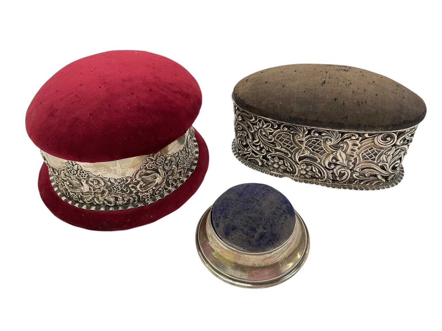 Lot 234 - Two Victorian silver mounted pin cushion jewellery boxes both with embossed scroll decoration, together with a smaller 1920s silver mounted pin cushion trinket box