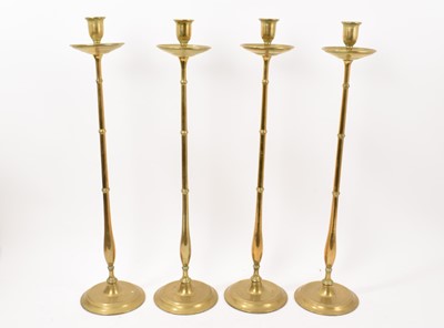 Lot 987 - Unusual set of four 19th century brass altar candlesticks, of slender form on spread foot, 55cm high