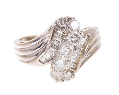 Lot 703 - Diamond crossover ring with seven graduated brilliant cut diamonds flanked by six graduated baguette cut diamonds in a channel setting with reeded shoulders on an 18ct white gold shank. Ring siz...