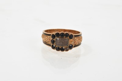 Lot 651 - George IV 18ct gold and black enamel mourning ring, the bezel with glazed compartment surrounded by black glass stones, the tapered foliate band with black enamel borders, engraved'In memory of...