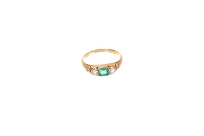 Lot 657 - Victorian emerald and diamond three stone ring with a central emerald flanked by two old cut diamonds in gold setting with carved gold shoulders, ring size L.