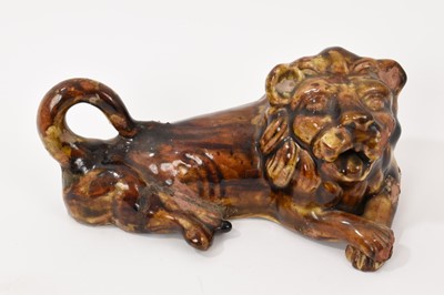 Lot 336 - A 19th century treacle glazed pottery figure of a seated lion, 19.5cm wide