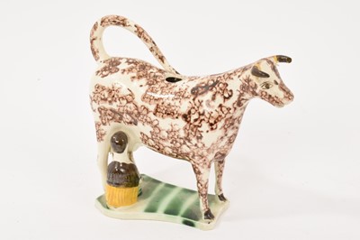 Lot 343 - An English creamware pottery cow creamer, circa 1800, charmingly modelled with kneeling milkmaid and pail, decorated in Pratt colours, old label to base, 14cm high