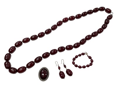 Lot 1072 - Simulated cherry amber necklace with large polished oval beads, together with a pair of similar earrings, bracelet and brooch