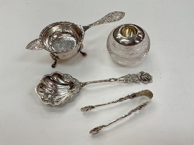 Lot 1037 - Silver mounted cut glass vesta globe, silver tea strainer with bowl, German white metal sugar tongs and preserve spoon