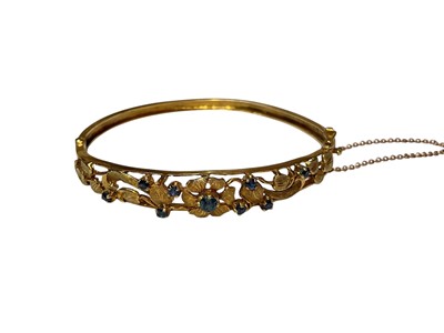 Lot 112 - 1970s 9ct gold and sapphire hinged bangle with pierced floral decoration (London 1971)